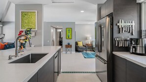 A modern kitchen with a central island, stainless steel appliances, and a knife rack. - Desert Gem - Bold Design, Poolside Fun, Spa, BBQ & Views (Palm Springs)