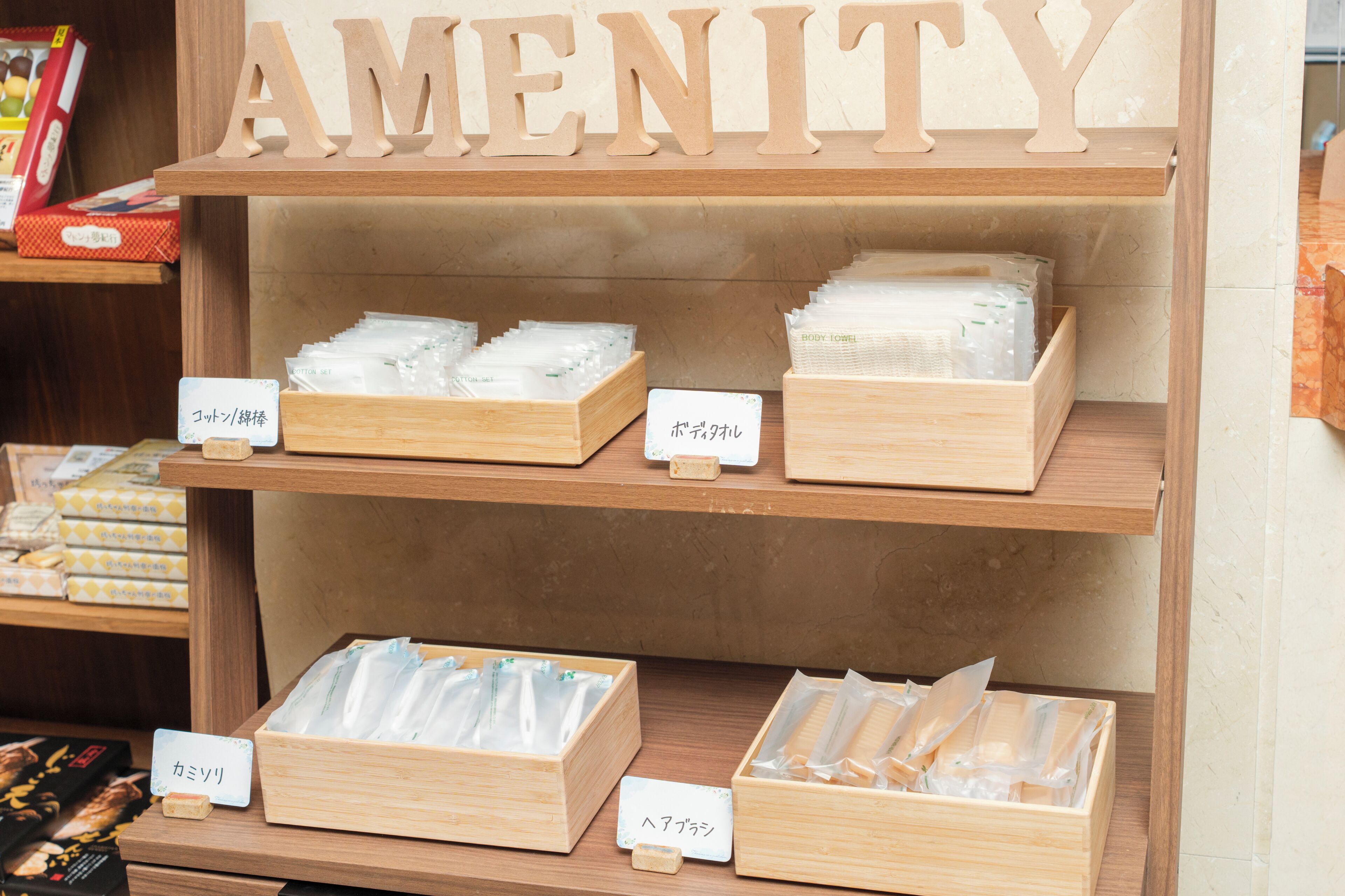 A wooden shelf with the word 'AMENITY' above it, containing various packaged items.