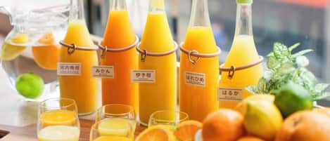 Botellas de jugo de naranja, vasos y naranjas sobre una mesa de madera.