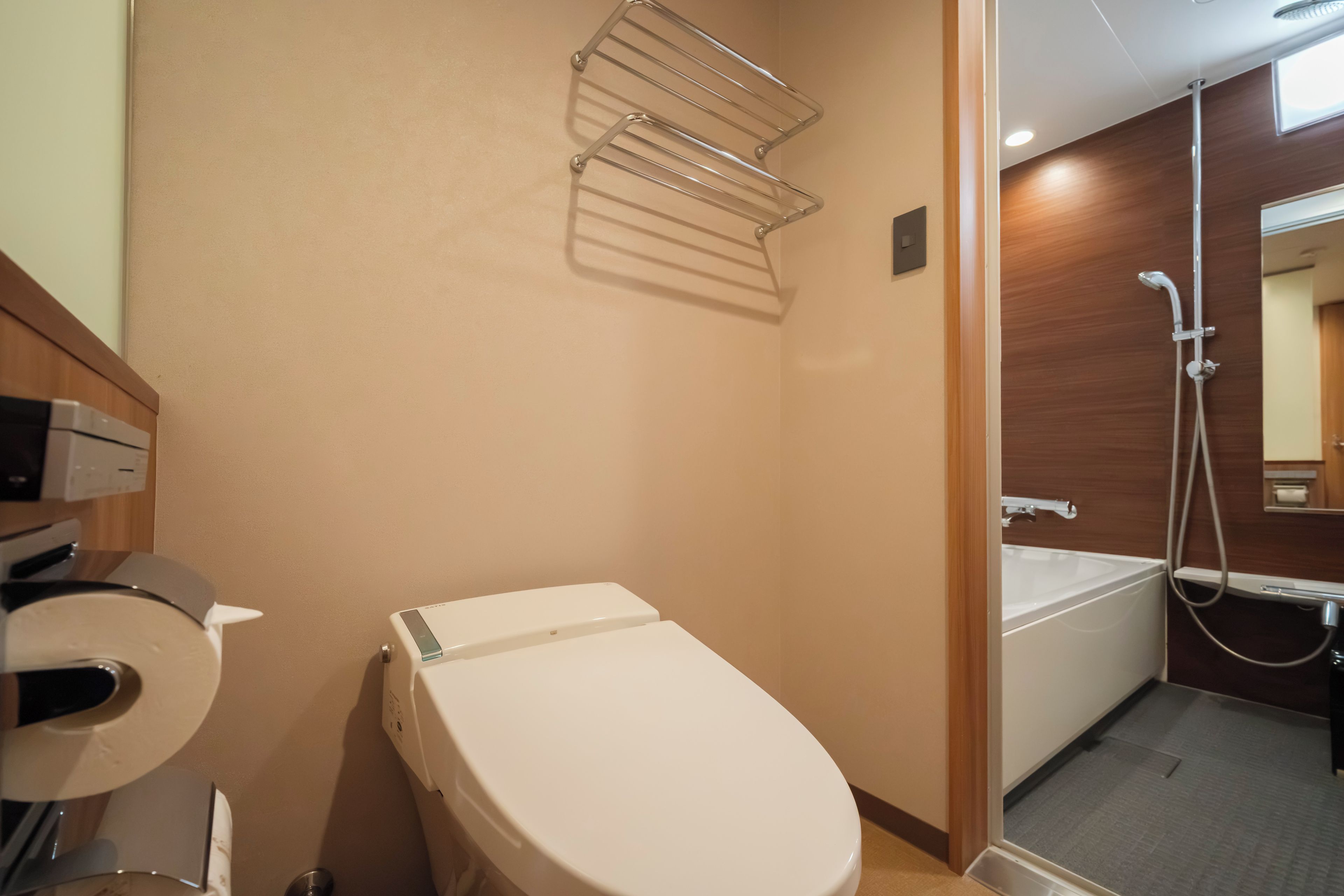 Egy modern fürőszoba, amelyben WC, zuhanyzó és törölközőtartó található.