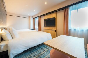 Habitación de hotel con cama, televisor montado en la pared y una mesita.