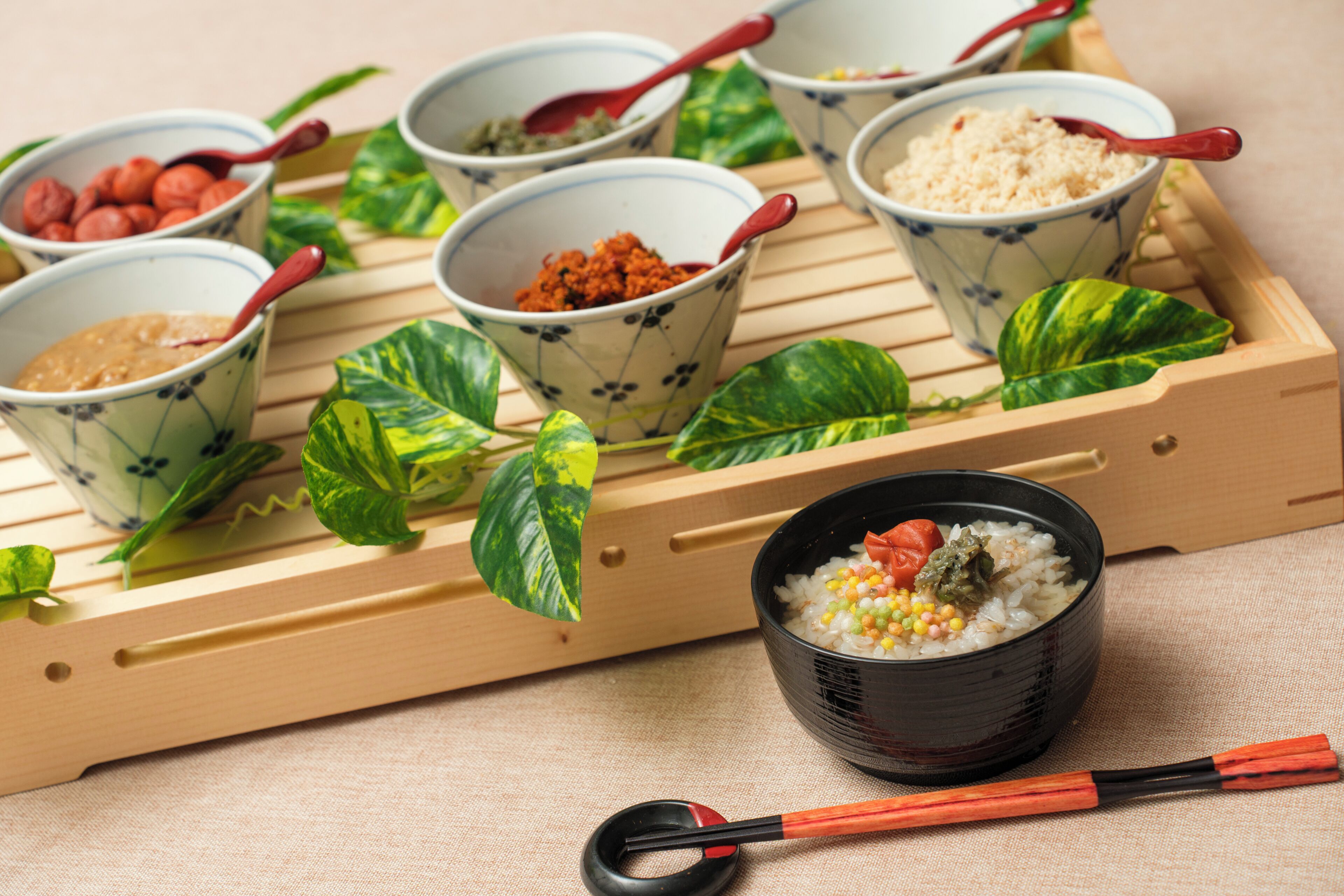 A tray with various bowls of food, a black bowl with a spoon, and a pair of chopsticks.