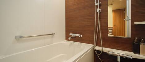 A modern bathroom with a white bathtub, wooden panel wall, and a mirror above the sink.