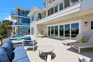Une maison moderne dotée d’une piscine, d’un espace salon extérieur et de grandes fenêtres.