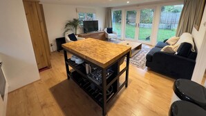 Un salon moderne avec une table à manger en bois, un canapé noir et un téléviseur.