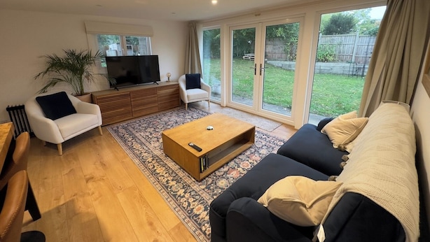 Un salon spacieux avec un grand canapé, une table basse et un téléviseur posé sur un meuble en bois.