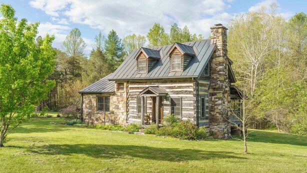 A log cabin with a stone chimney, a front porch, and a surrounding grassy area. - Hummingbird's Rest - Wine Country Cabin Retreat (Dyke)