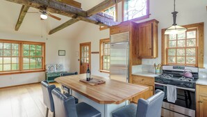 A kitchen with wooden cabinets, a large island with bar stools, a stainless steel refrigerator, and a gas stove. - Hummingbird's Rest - Wine Country Cabin Retreat (Dyke)