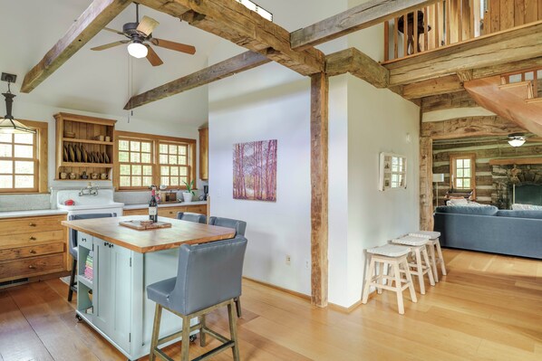 Una cocina amplia con vigas de madera, un comedor con taburetes y una sala de estar con sofá.
