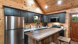 Une cuisine moderne avec des murs en bois, un réfrigérateur en acier inoxydable, un four à micro-ondes et un grand îlot central doté de tabourets.