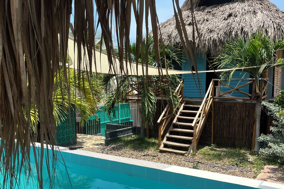 Una piscina con una estructura de techo de paja al fondo.