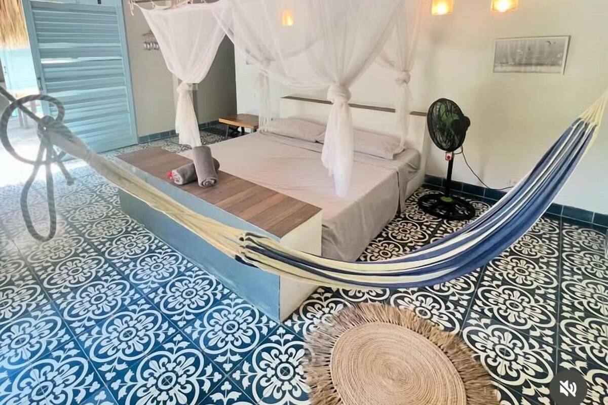 Una cama hamaca con dosel, un ventilador y un suelo estampado.