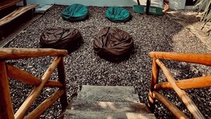 Un área de piscina con una estructura de techo de paja, una hamaca y sillones de tumba piedra.