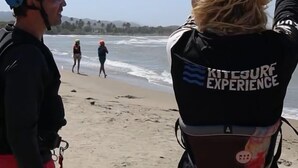 Escena de playa con gente practicando kitesurf.