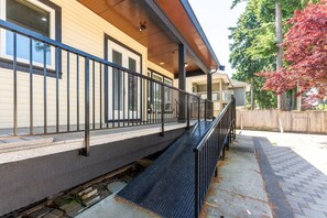 A residential building with a covered porch, a metal staircase, and a wooden deck.