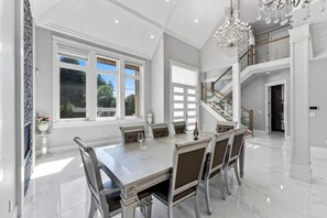 A spacious dining area with a large table, multiple chairs, and a chandelier.