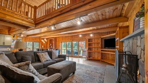 A spacious living room with a large sectional sofa, a stone fireplace, and a television.