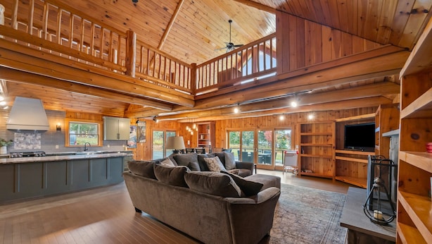 A spacious living area with a wooden ceiling, a large sofa, and a kitchen area with a central island.