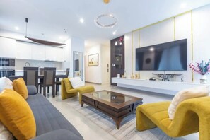 A modern living room with a sofa, armchairs, a coffee table, and a flat-screen TV mounted on the wall.