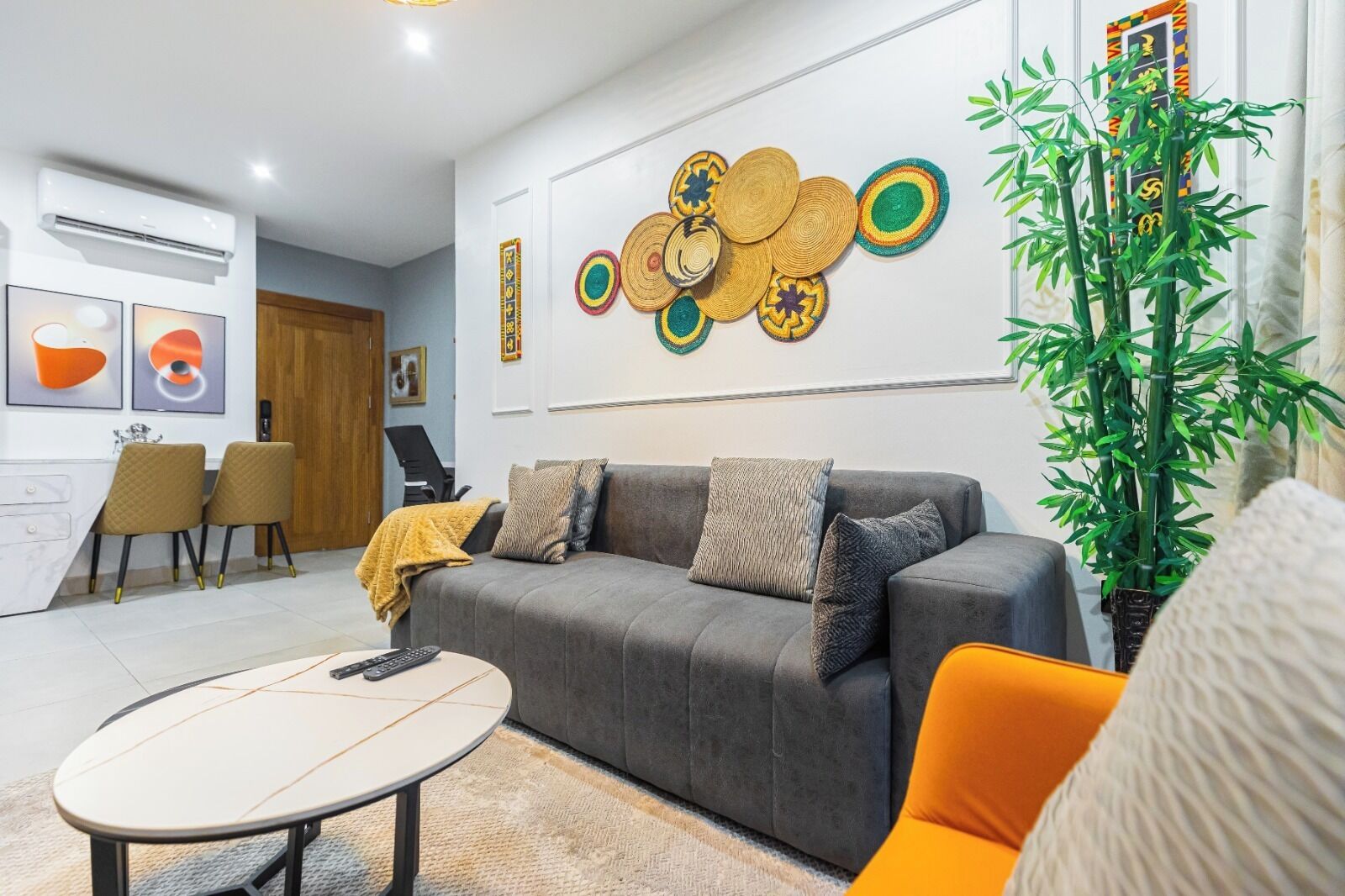 A modern living room with a grey sofa, a round coffee table, and a large wall art piece.