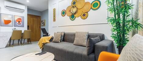 A modern living room with a grey sofa, a round coffee table, and a large wall art piece.