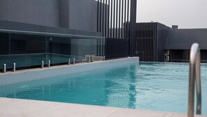A modern indoor swimming pool with clear water, surrounded by a glass railing and a minimalist architectural design. - NOVA-BlueWaters Property Management (Accra)