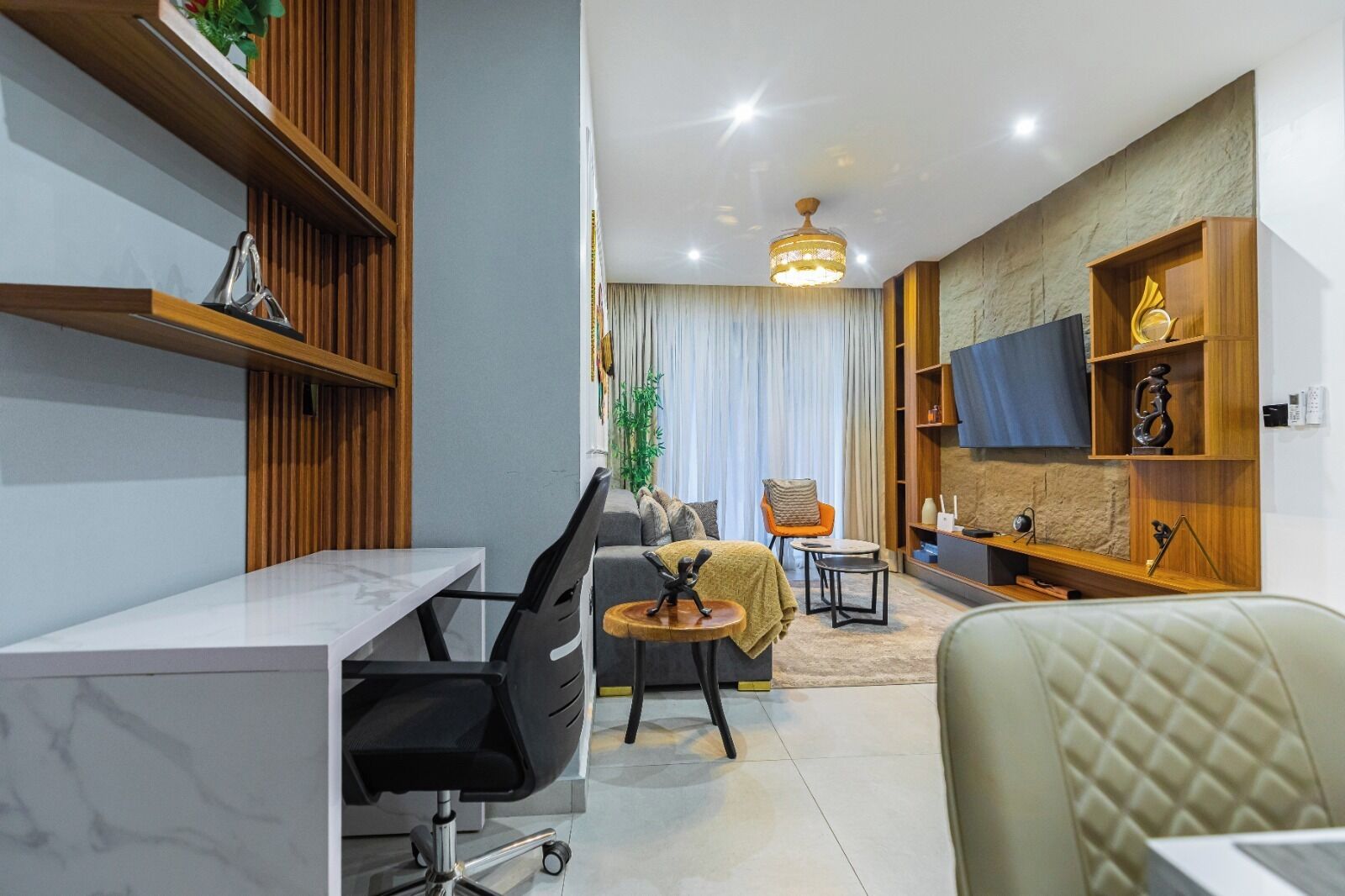 A modern living room with a dining area, a sofa, a TV, and a wooden shelf.