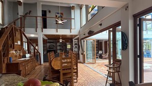 A spacious kitchen with a dining area, a staircase, and a view of the outside. - Casa Corazón - Spacious 6 Bedroom Beachfront Villa (Placencia)