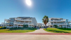 A modern multi-story hotel with balconies, a central entrance, and a well-maintained lawn. - Shared Pool, Hot Tub, Pet Friendly (Port Aransas)