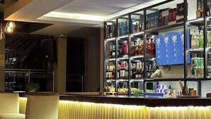 A bar area with a wooden panel back wall, a glass display case with bottles, and a seating area with chairs. - Zuri Place Hotel (Oyugis)