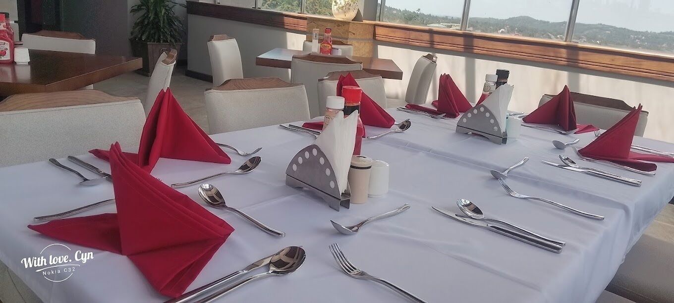 A dining table set with red napkins, silverware, and a white tablecloth.