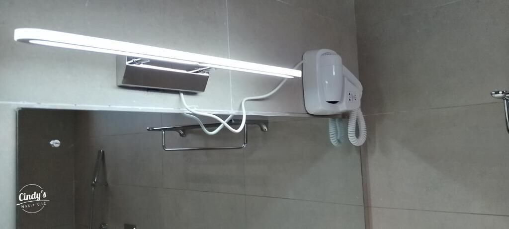 Ein modernes Badezimmer mit Wandhaartrockner, Handtuchhalter und einer Leuchte.