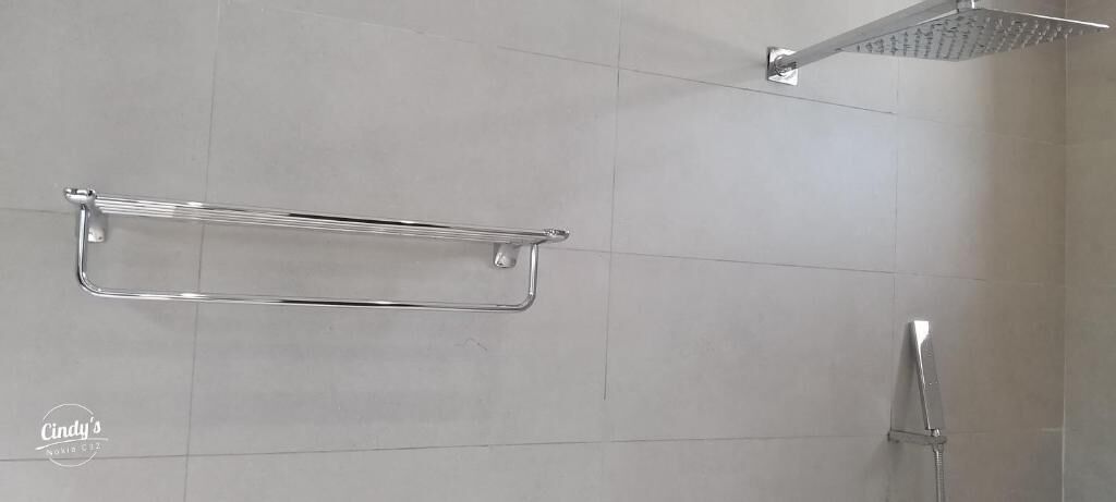 A bathroom with a shower, a towel rack, and a toilet.