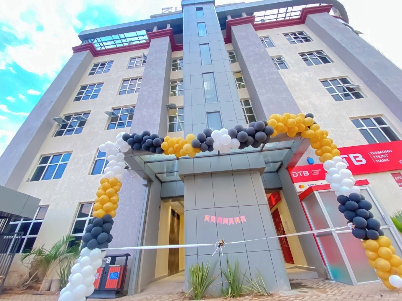 Un bâtiment à l’architecture moderne, doté d’une entrée centrale surmontée d’une arche décorative faite de ballons.