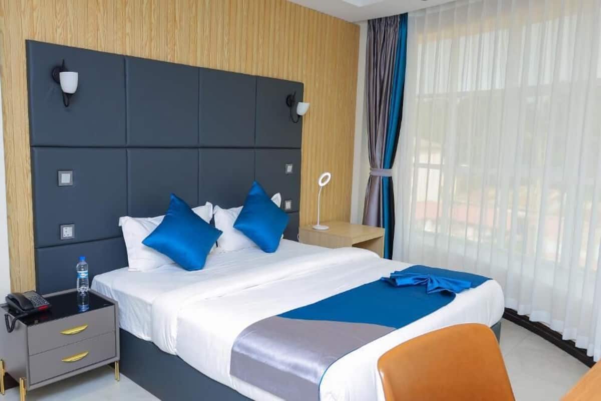 A hotel room with a large bed, bedside tables, a desk, and a chair.