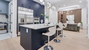 Une cuisine moderne avec des meubles de couleur sombre, des appareils en acier inoxydable et un îlot central doté de tabourets de bar.