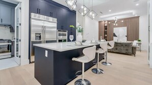 Une cuisine moderne avec des meubles de couleur sombre, des appareils en acier inoxydable et un îlot central doté de tabourets de bar.