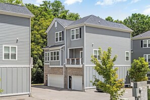 Un immeuble résidentiel à deux étages, doté d’un garage, d’un balcon et de fondations en briques.