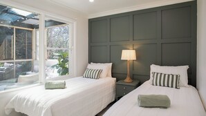 A bedroom with two beds, a window, and a nightstand with a lamp. - Highland Heart Cottage, Newly Renovated, Spacious & Family Friendly (Bowral)