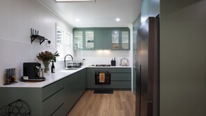 A modern kitchen with a built-in oven, a coffee machine, and a sink. - Highland Heart Cottage, Newly Renovated, Spacious & Family Friendly (Bowral)