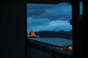 Vista de un edificio con estructura escalonada y aguja, visible a través de una ventana con barandilla metálica.