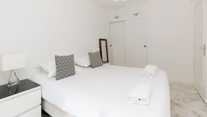 Una habitación de hotel con cama, mesita de noche, lámpara, espejo y armario.