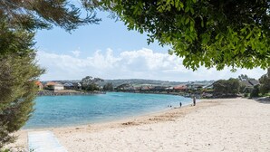 A beach with clear blue water, a sandy shore, and houses in the background. - The Lake House—Spacious Group Haven by the Bay (Victor Harbor)