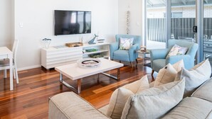 A modern living room with a flat-screen TV, a sofa, a chair, and a coffee table. - The Lake House—Spacious Group Haven by the Bay (Victor Harbor)