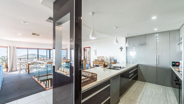 A modern kitchen with a central island, stainless steel appliances, and a large window overlooking a scenic view. - BaeView: Panoramic Group Stay Above Encounter Bay (Encounter Bay)