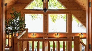 A wooden interior with a balcony, a potted plant, and a view of the outdoors. - Lake Bemidji retreat- modern, cozy cabin spacious enough for family and friends. (Bemidji)