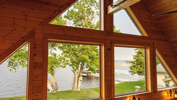 A cabin with large windows offering views of a lake and trees. - Lake Bemidji retreat- modern, cozy cabin spacious enough for family and friends. (Bemidji)