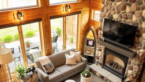 A cozy living room with a stone fireplace, a sofa, and a television. - Lake Bemidji retreat- modern, cozy cabin spacious enough for family and friends. (Bemidji)