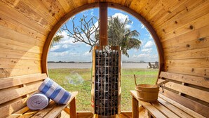 Eine Holzsauna mit rundem Fenster, Bänken, einem Handtuch und einem Steinkamin.