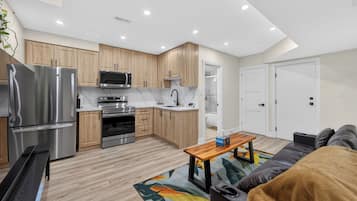 Una cocina moderna con electrodomésticos de acero inoxidable, armarios de madera y una isla central.